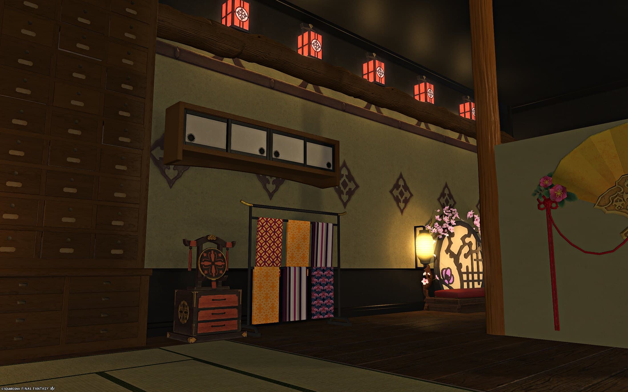 The entrance wall — tall chests of small drawers, a rack of hanging kimono fabrics, a folding fan on the wall and red lanterns along the ceiling beam