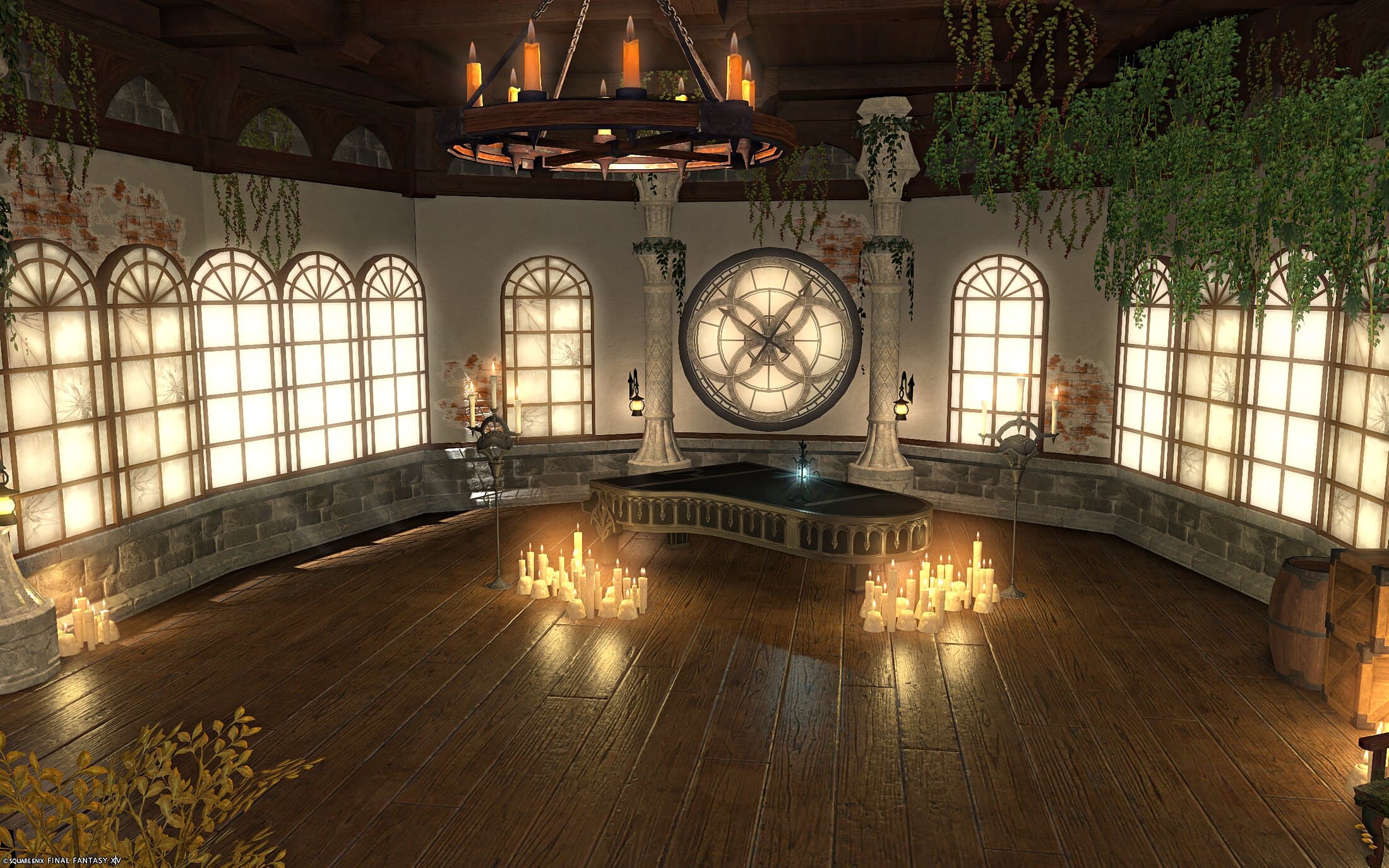 The room upstairs — a black grand piano in the middle of the floor ringed with clusters of candles, glowing arched windows along the curved walls above a band of grey stone, a huge round clock-face window between two ivory pillars, a wooden ring chandelier of candles overhead, and ivy hanging from the beams