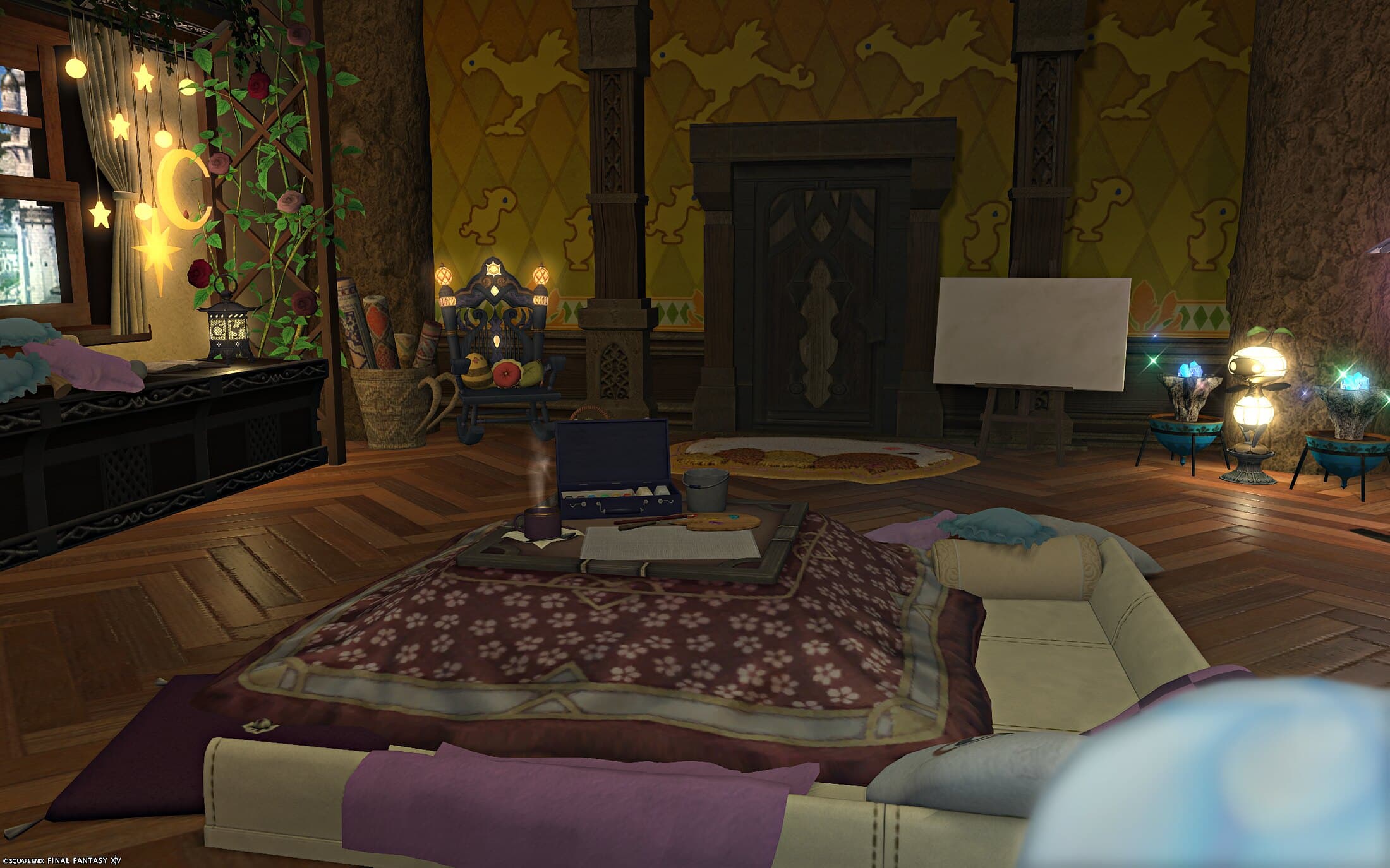 The studio — gold chocobo-motif wallpaper, a low table with a maroon throw and scattered cushions, and an easel holding a blank canvas