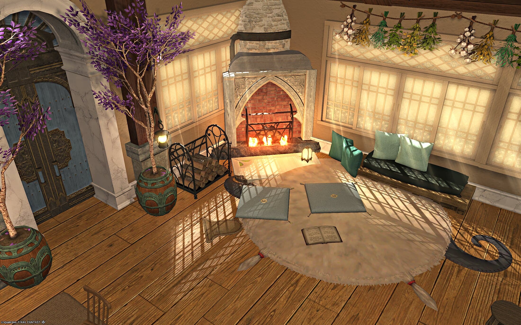 The sitting area from the entrance — potted wisteria trees either side of a carved blue door, an iron firewood rack, and the lit fireplace beyond floor cushions and a green sofa
