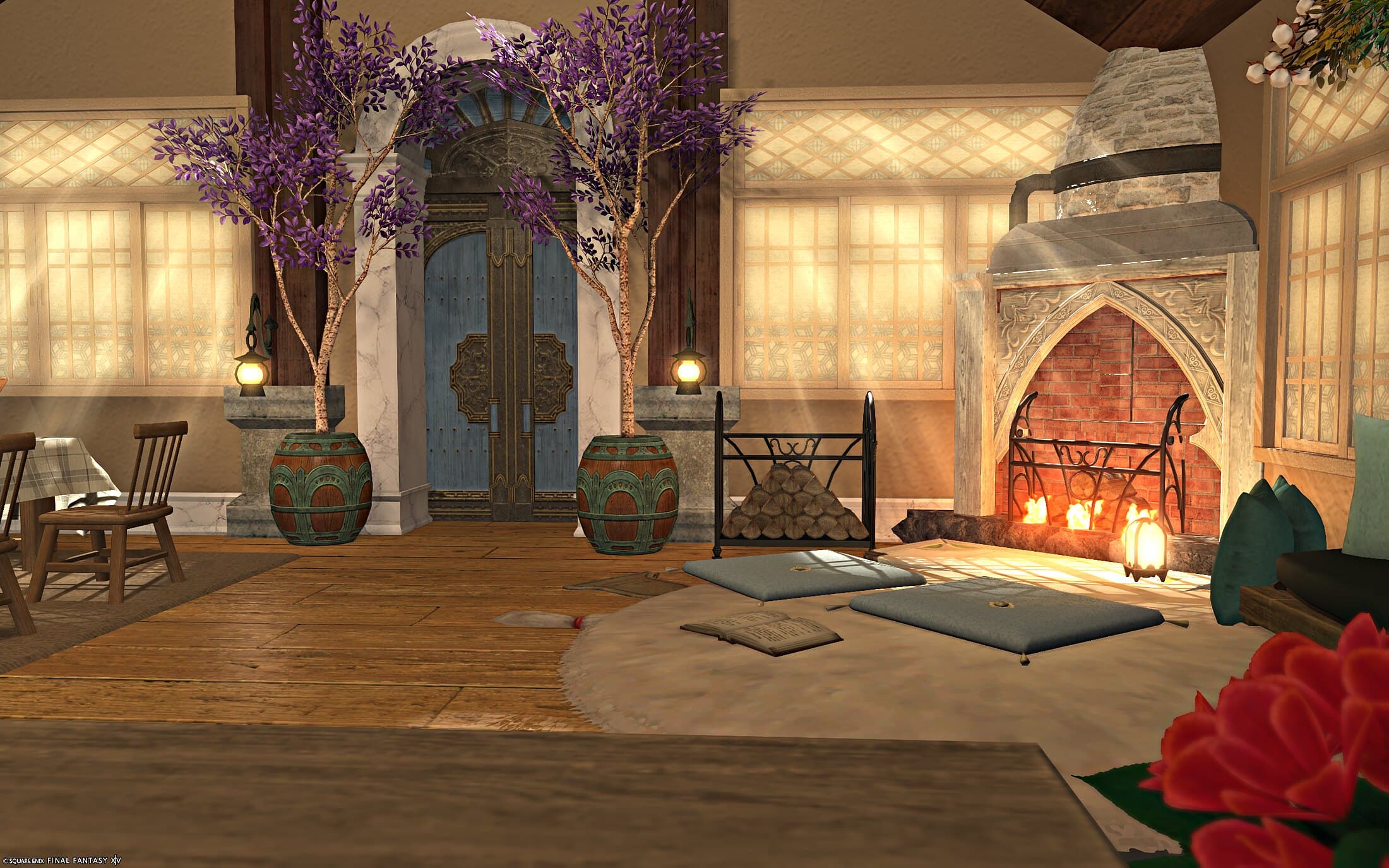The entrance — a carved blue door between potted wisteria trees, an iron firewood rack, and pale blue floor cushions catching light from the fireplace side