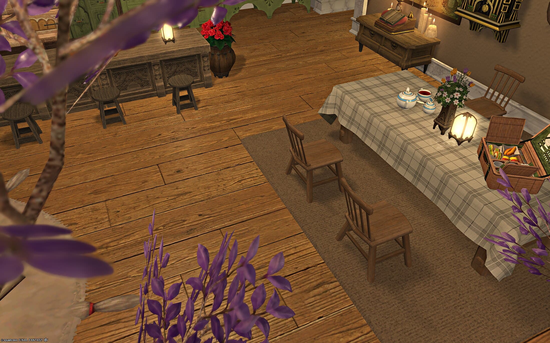 The dining table seen wide, a woven picnic basket set on it beside a lantern and a vase of flowers, wisteria in the foreground