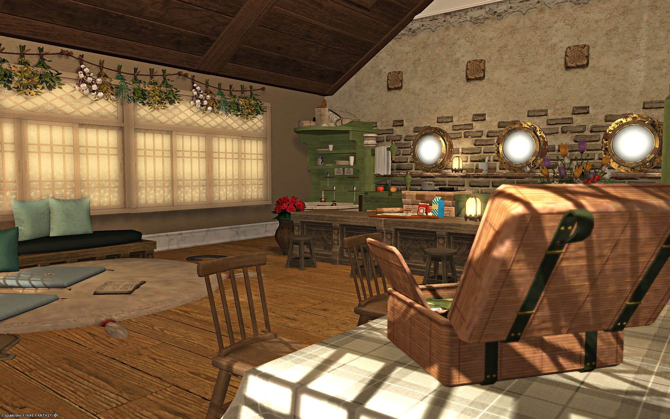 The kitchen bar seen past a leather travelling trunk — a rustic brick wall set with three gilt porthole windows, green cabinetry and a row of stools