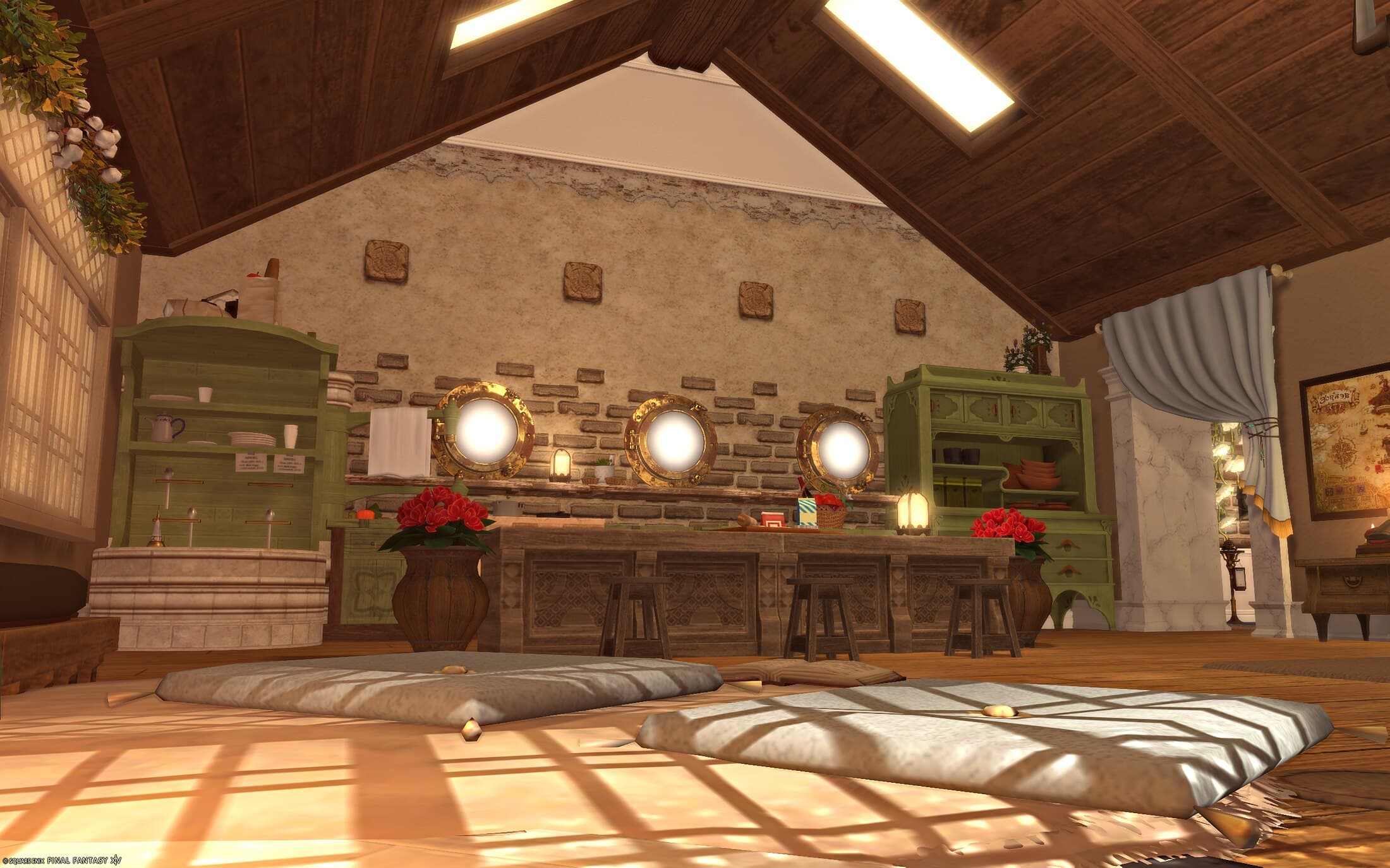 The kitchen wall seen past the sitting area's floor cushions, green cabinetry and the three porthole windows set into brick