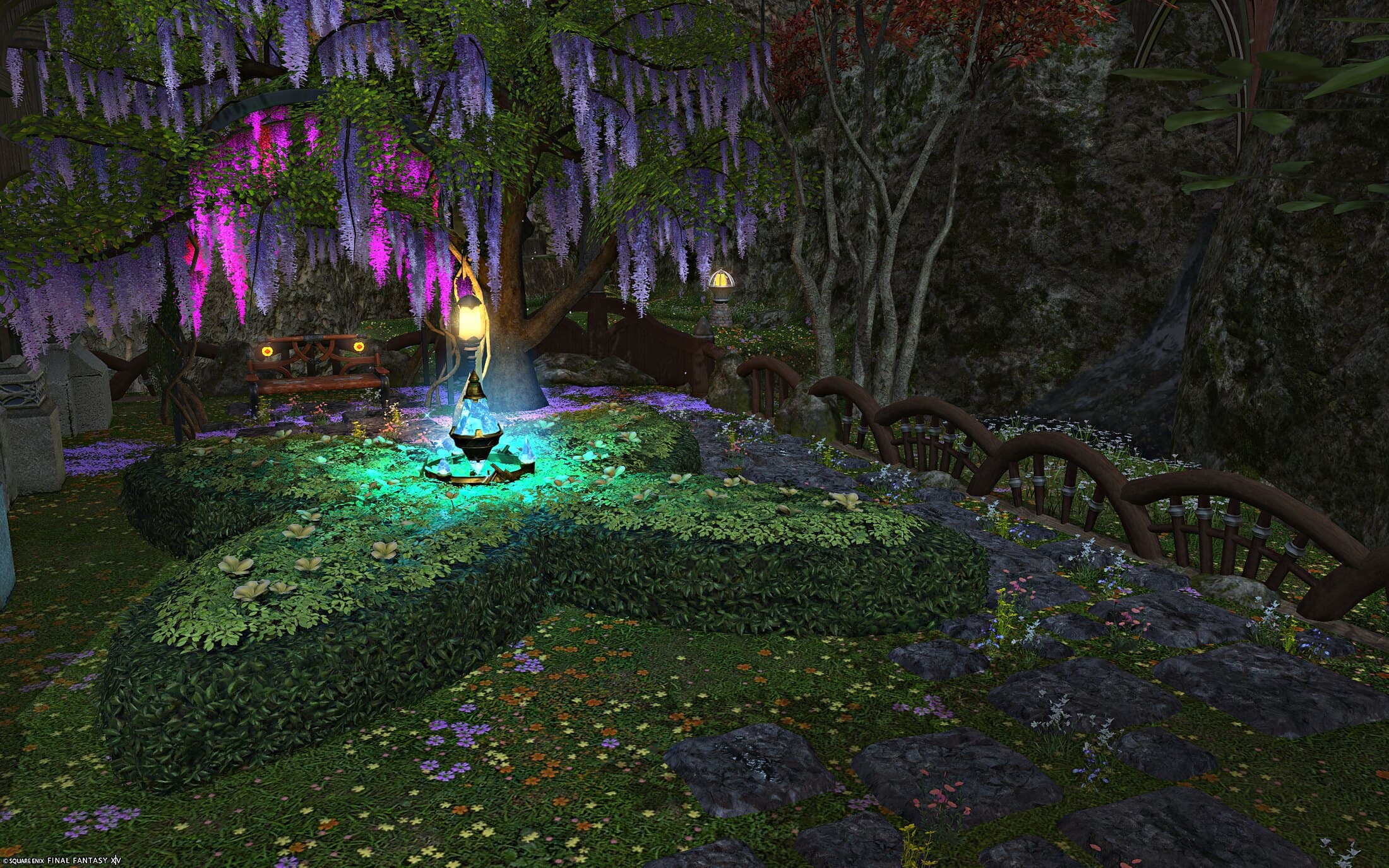 The garden fountain seen from a bench, stepping stones leading away through wisteria and a wooden fence