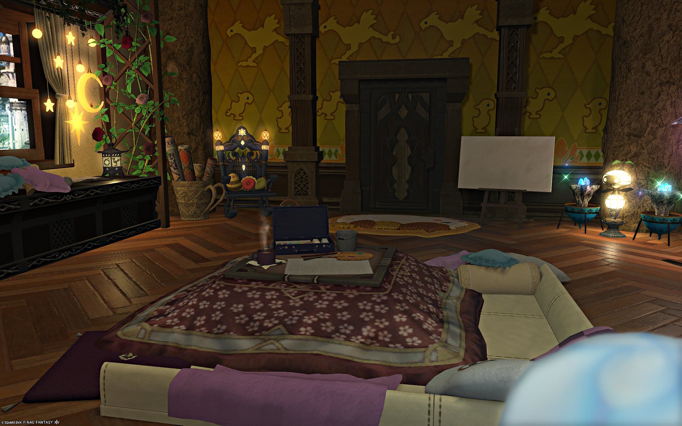 The studio — gold chocobo-motif wallpaper, a low table with a maroon throw and scattered cushions, and an easel holding a blank canvas